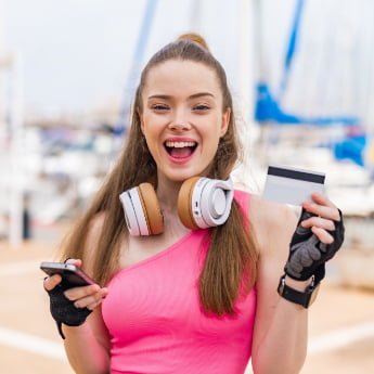 Tap to pay use case for fitness, sport lady with phone and credit card smiling