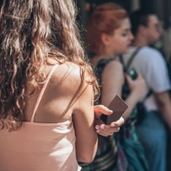 Tap-to-pay-use-case-for-queue-busting-lady-waiting-in-line-with-smartphone-waiting-to-pay-for-tickets